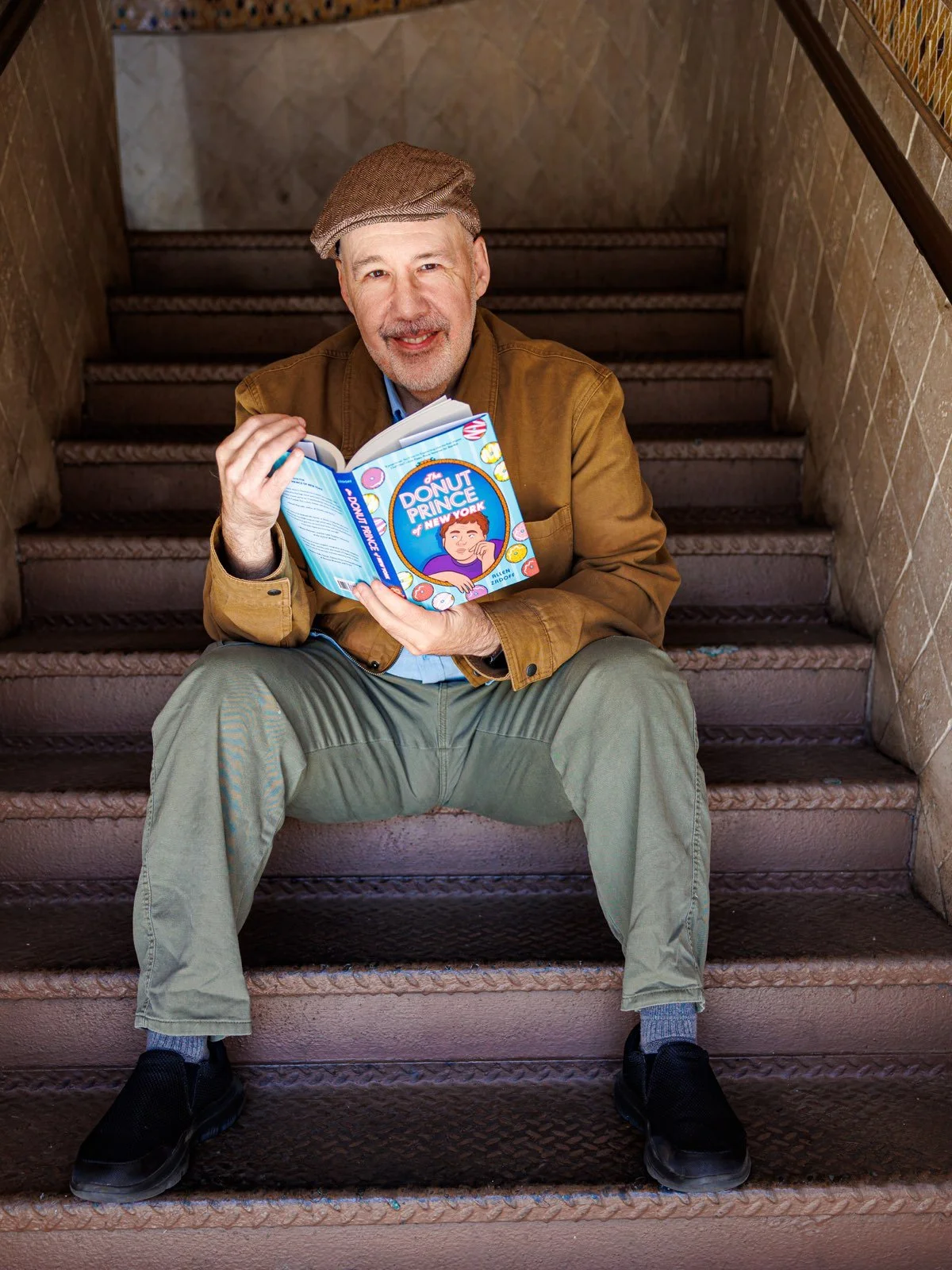 Allen Zadoff sitting on a staircase with The Donut Prince of New York